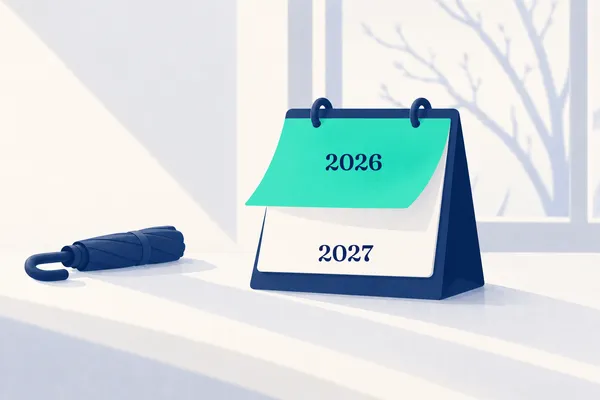 Ein navyblauer Tischkalender, dessen mintfarbenes Blatt 2026 sich umblättert und 2027 freigibt, daneben ein geschlossener Schirm im Winterlicht.